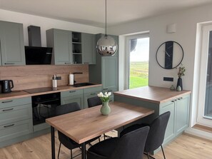 Una cocina moderna con encimera de madera, armarios grises y un comedor con mesa y sillas.