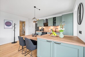 A modern kitchen with teal cabinets, a wooden countertop, and a hanging pendant light. - The View G03 Wyk - Sea view, terrace, garden furniture, 2nd floor, car parking (Dagebüll)