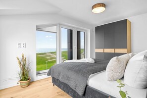 A bedroom with a large bed, a view of the outdoors, and a modern design. - The View G03 Wyk - Sea view, terrace, garden furniture, 2nd floor, car parking (Dagebüll)