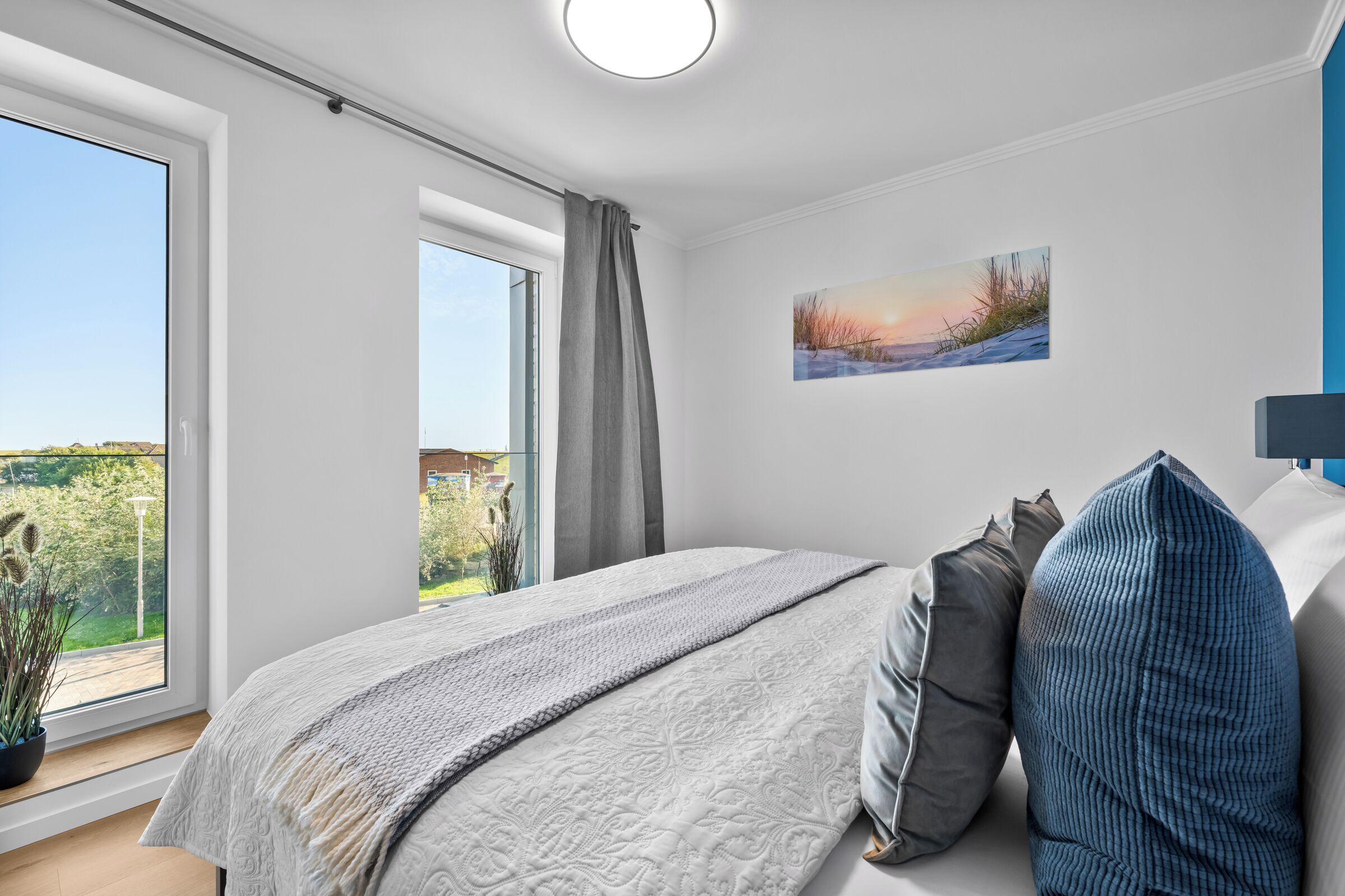 Ein Schlafzimmer mit einem großen Bett, Blick ins Grüne und einem Bild an der Wand.