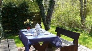 A picnic table set outdoors with a tablecloth, plates, cups, and a teapot. - Comfortable vacation apartment with terrace and family facilities in Garding (Garding)