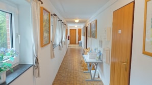 A hallway with a tiled floor, wooden doors, and a table with items on it. - Künstlergarten Apartment 2: Comfortable vacation accommodation with terrace and garden i (Garding)