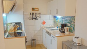 A compact kitchen with white cabinets, a wooden countertop, a coffee maker, a toaster, and a sink. - Künstlergarten Apartment 2: Comfortable vacation accommodation with terrace and garden i (Garding)