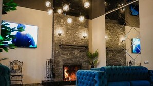 A modern lobby with a stone fireplace, a blue sofa, and a television mounted on the wall.