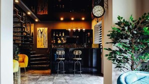 A bar area with a clock, two stools, and a plant.
