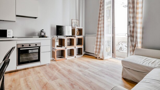 Une cuisine moderne avec des meubles blancs, un four encastré et un coin repas comprenant une table et des chaises.