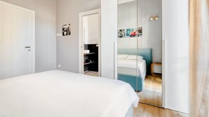 Une chambre à coucher avec un lit, une armoire avec un miroir et une porte donnant sur une salle de bain.