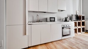 Une cuisine moderne avec des meubles blancs, un four à micro-ondes, une machine à café et un four.