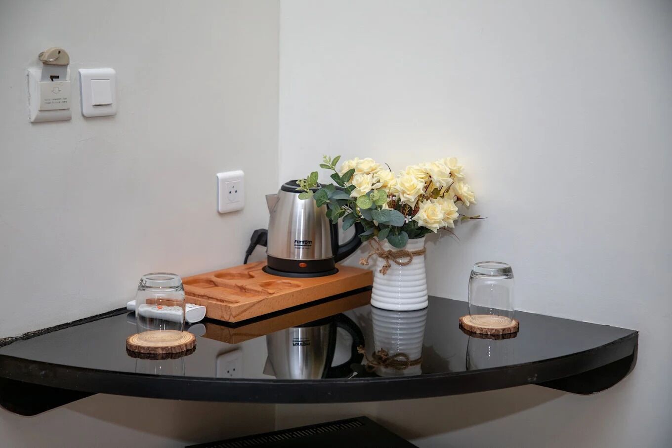 A table with a coffee maker, a vase of flowers, and two glass jars.