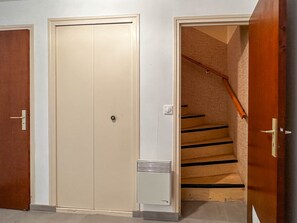 A hallway with a closed beige door, a white door, and a wooden staircase with a handrail. - Spacious villa for 10 guests - Park - Wi-Fi, Air Conditioning (La Palmyre)