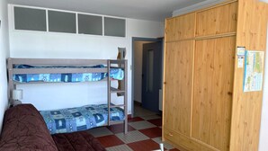 Um quarto de dormitório com beliches, um guarda-roupa e um mapa na parede.