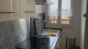 Uma cozinha moderna com um fogão por indução preto, um exaustor de aço inoxidável e uma janela com vista para o exterior.