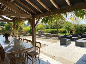 Patio esterno con zona pranzo coperta, tavoli da picnic e posti a sedere all'aperto.