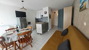 Un espace de vie compact comprenant un coin repas, une kitchenette et un canapé.