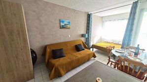 Une pièce confortable avec un canapé, une table à manger et des chaises, et une vue sur l’extérieur.
