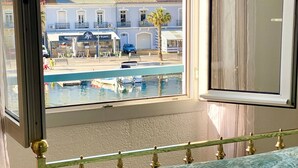 Une chambre avec vue sur une piscine, un bâtiment abritant un restaurant et une voiture garée.