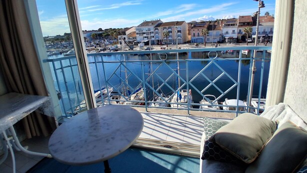 Un balcon donnant sur une marina, avec une table et un canapé.