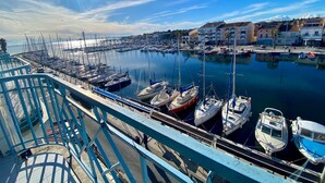 Un port de plaisance avec des bateaux amarrés, un ciel dégagé et des bâtiments en arrière-plan.