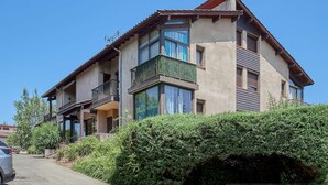 Um edifício residencial com vários andares, varandas, janelas grandes e um céu claro.
