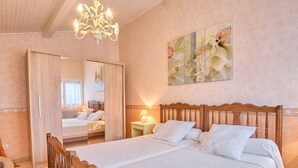 Quarto com cama de madeira, um candelabro, um espelho e um quadro com flores na parede.