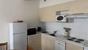 A compact kitchen with a refrigerator, microwave, stove, and sink. - Central Apartment for 4 - Parking Included (Royan)