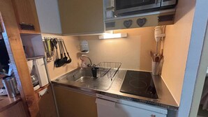Una cucina compatta con microonde, lavandino e piano cottura.