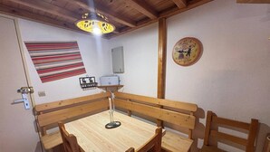 Zona pranzo con tavolo e panche in legno, lampadario, decorazione murale a righe e orologio a parete.