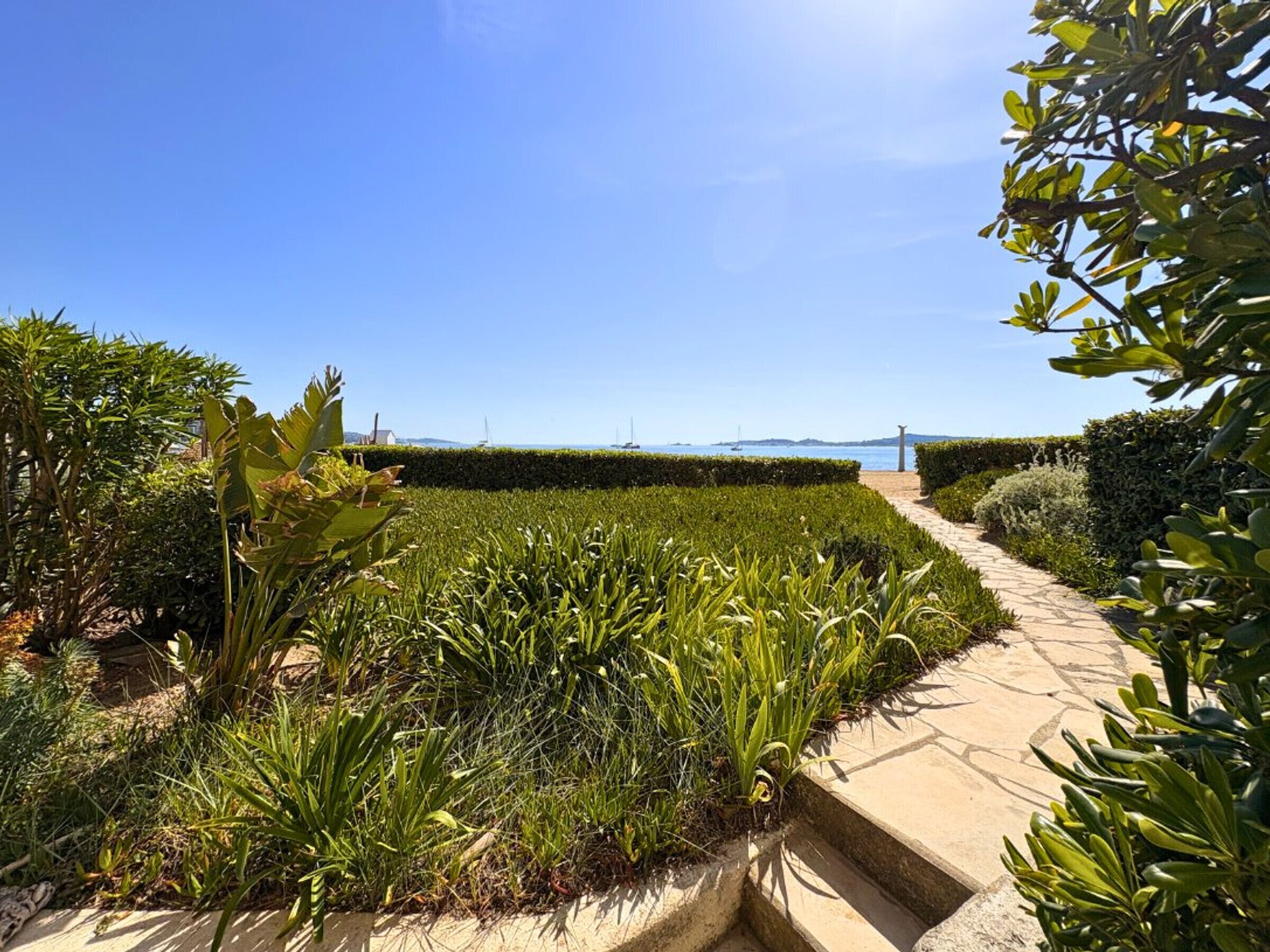 Ein angelegter Garten mit einem Weg, der zum Blick auf das Meer führt.