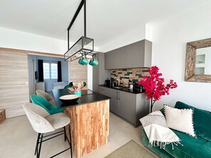 A modern kitchen with a wooden island, bar stools, and a dining area with a green sofa. - Renovated Ground Floor Apartment - Direct Beach Access - Port Grimaud - 4 Guests (Port Grimaud)