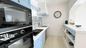 Una cucina compatta con forno integrato, microonde e orologio a parete.