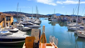 Una marina con barche ormeggiate, cielo sereno e edifici sullo sfondo.