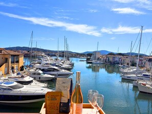 A marina with boats docked, a clear sky, and buildings in the background. - 2-Bedroom Apartment with Air Conditioning and WIFI (Port Grimaud)