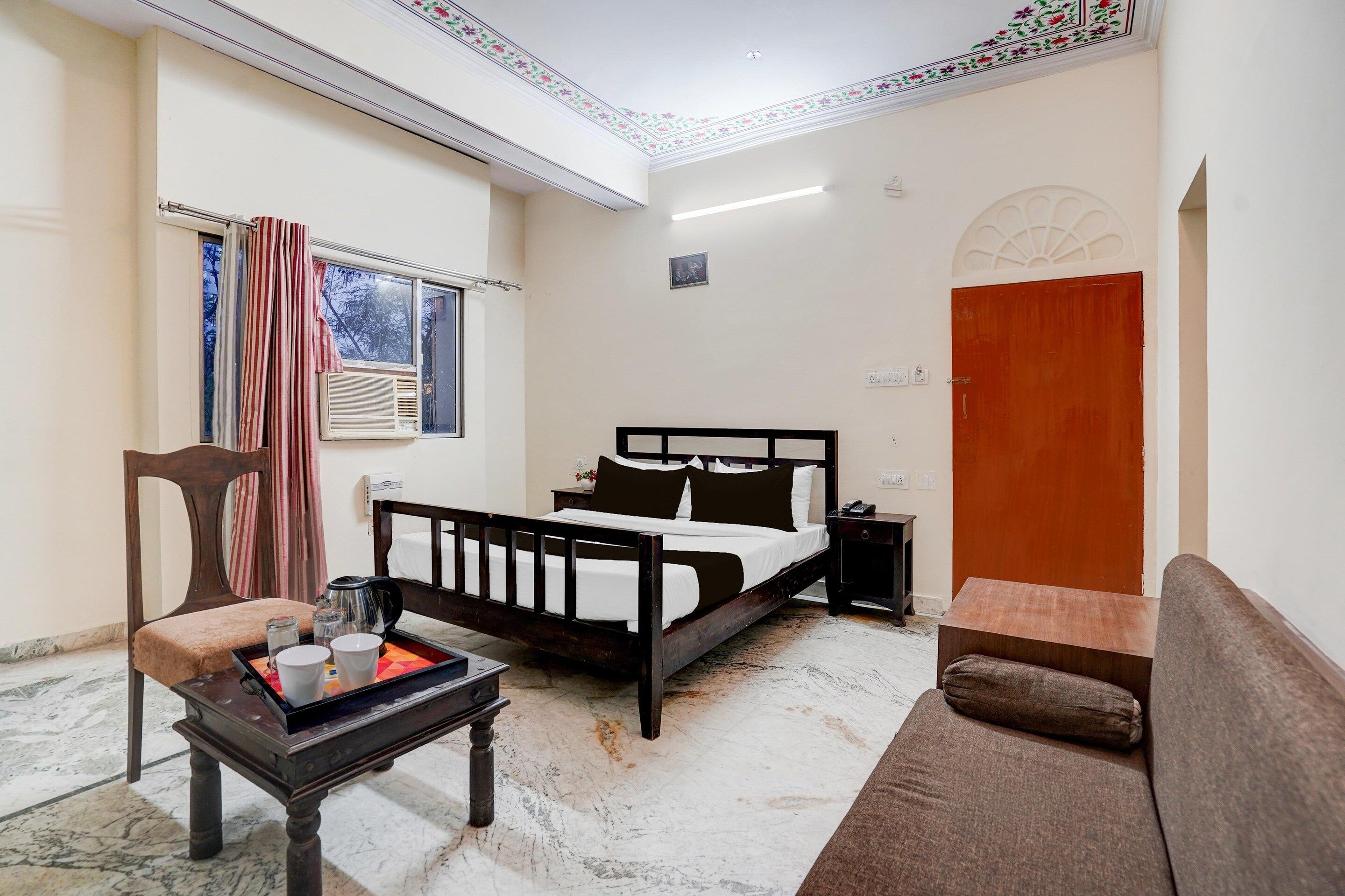 A bedroom with a bed, a sofa, a coffee table, and a chair.