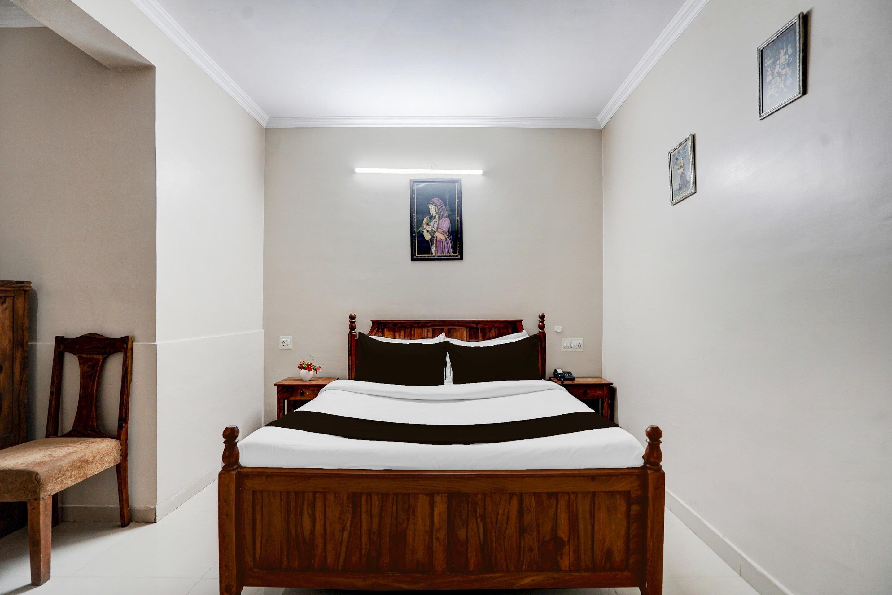 Un dormitorio con una cama de madera, una mesita de noche, una silla y un cuadro en la pared.