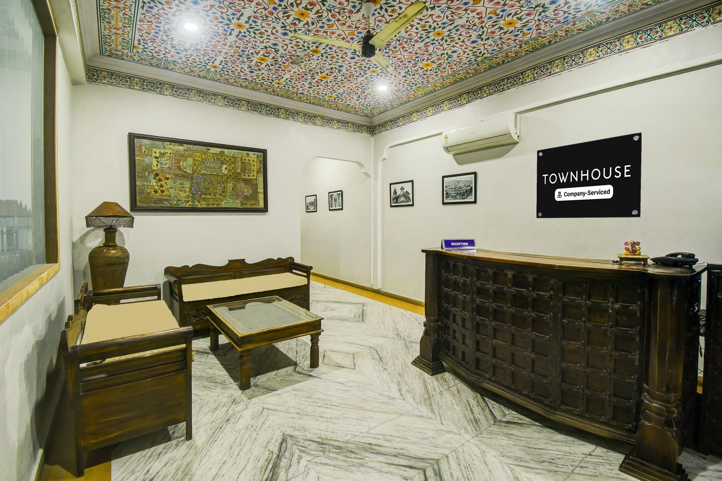Een receptiezone met een marmeren vloer, houten meubels, een plafond met ingewikkelde patronen, en een bord dat aangeeft dat het een bedrijfskamerwoning is.