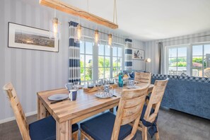 A dining area with a wooden table, chairs, and hanging pendant lights. - Luxurious thatched house in Zinnowitz - wellness, garden & fireplace (Zinnowitz)