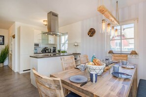 Una cocina moderna con una isla central, sillas de madera y una mesa de comedor dispuesta con platos y tazas.