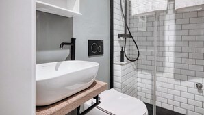 Et moderne badeværelse med en hvid vask, toilet og brusekabine i glas.