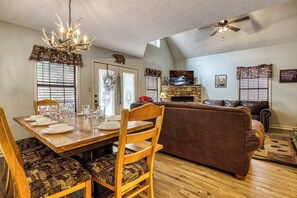 A dining area with a wooden table set for four, a brown sofa, and a fireplace.
