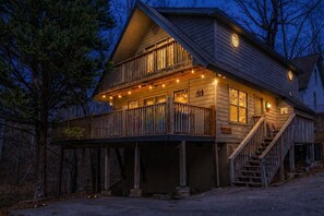 Una cabaña de madera con balcón, escaleras y luces colgantes.