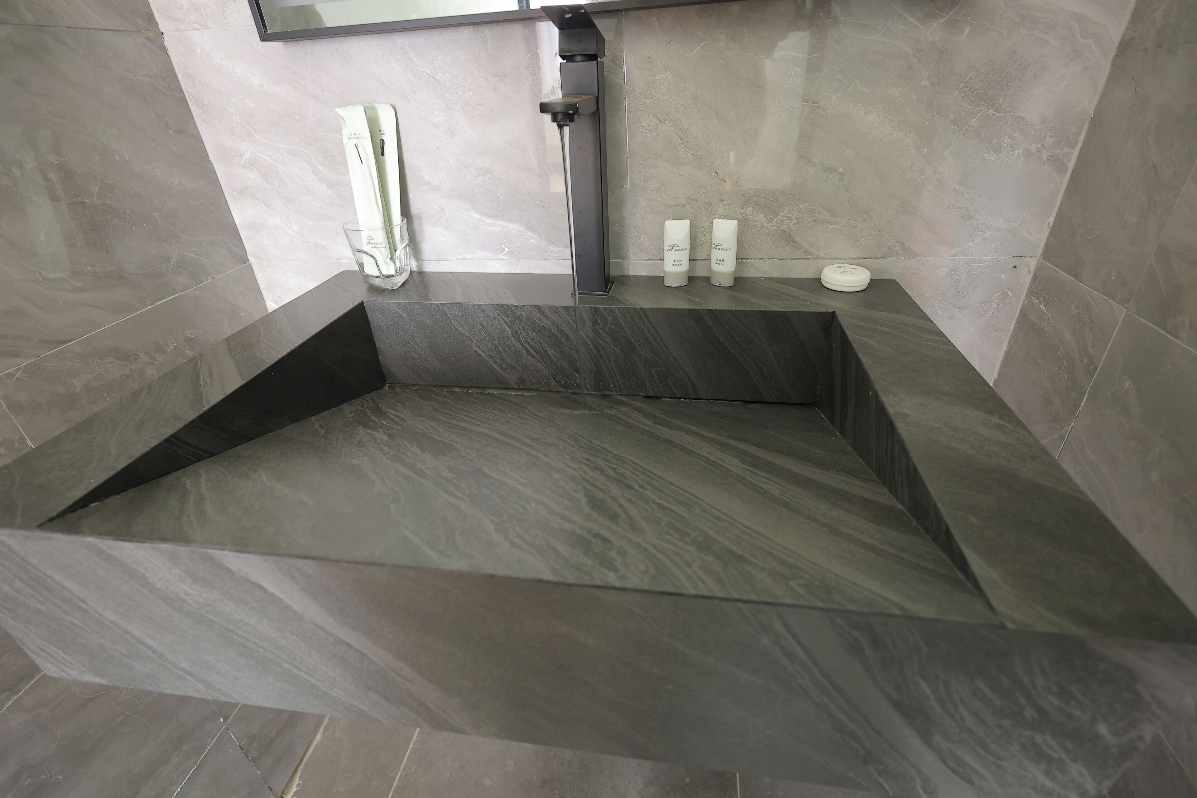 A modern bathroom with a large bathtub, a handheld showerhead, and two bottles of lotion on a shelf.