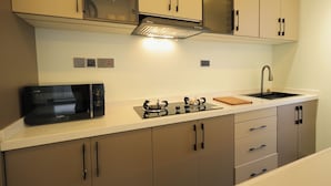 A kitchen with a microwave, stove, and sink. - Heritage Residences-Velvet Rouge 1BR (Kampala)