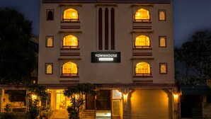 Un edifici amb un rètol que diu "TOWNHOUSE" i diversos balcons amb il·luminació càlida.