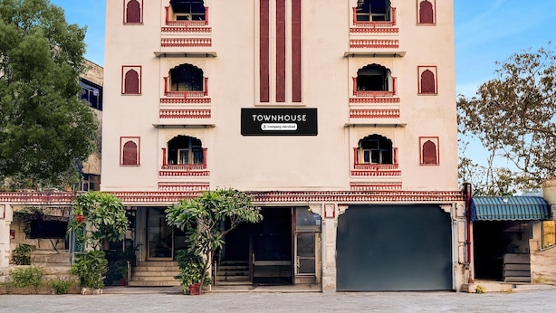 Una casa urbana amb un rètol que diu "TOWNHOUSE", una entrada central i una gran porta de garatge.