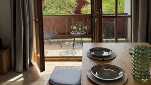 A dining area with a wooden table, grey cushions, and a green glass vase.
