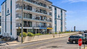 A multi-story hotel with balconies, a visible restaurant, and a stop sign. - Beautiful 1 bedroom oceanfront condo, free WiFi, linens included and an indoor pool located right on the boardwalk! (Ocean City)