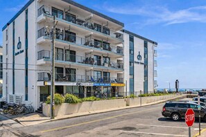 A multi-story hotel with balconies, a visible restaurant, and a stop sign. - Beautiful 1 bedroom oceanfront condo, free WiFi, linens included and an indoor pool located right on the boardwalk! (Ocean City)