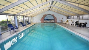 An indoor swimming pool with a covered roof, lounge chairs, and a mural of a beach scene. - Beautiful 1 bedroom oceanfront condo, free WiFi, linens included and an indoor pool located right on the boardwalk! (Ocean City)