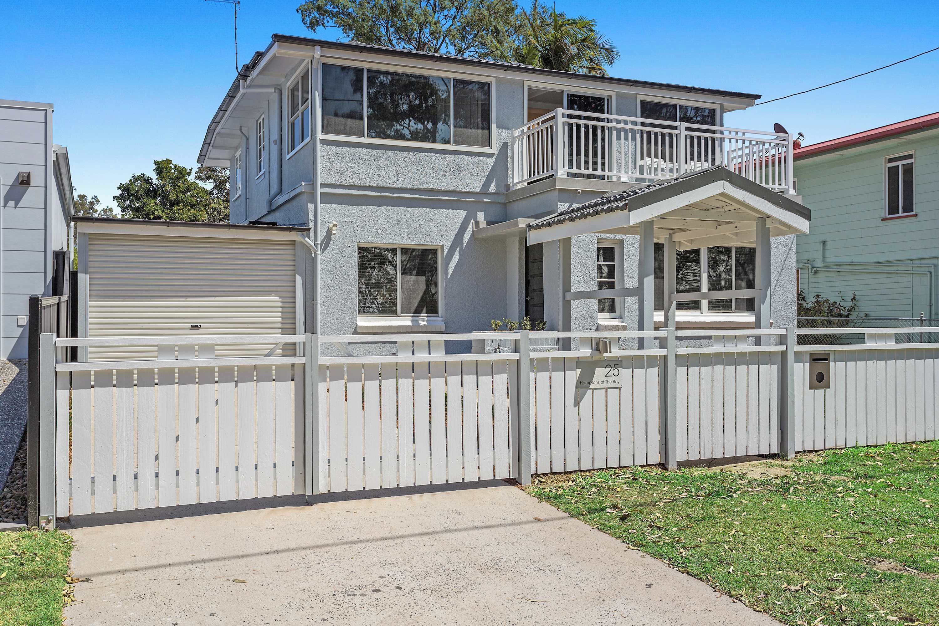 A two-story house with a garage, a balcony, and a fenced yard.