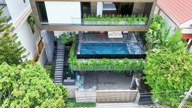 Un edificio moderno de varios pisos con jardín en la azotea, una piscina y una escalera que conduce a los niveles superiores.